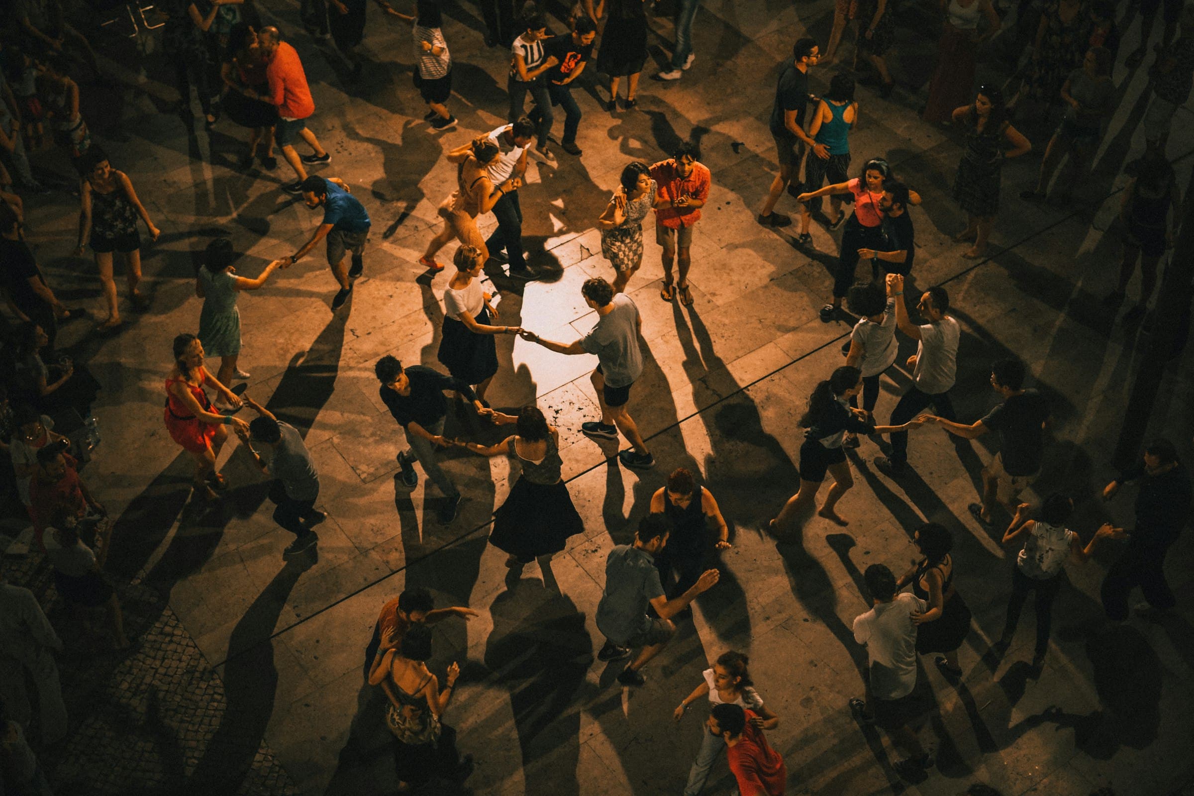 Una pista llena de parejas bailando bachata bajo la luz nocturna